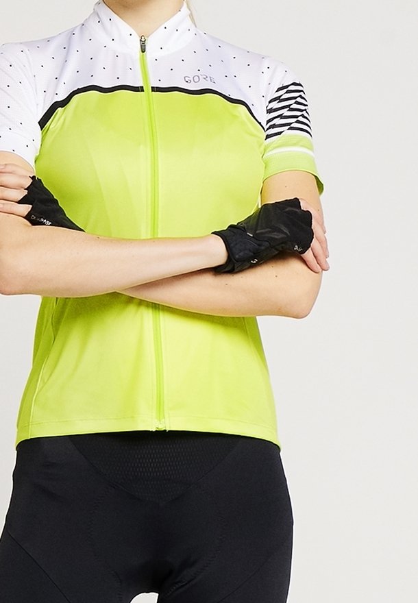 Camiseta de ciclismo de manga corta en un brillante verde lima, con un yugo blanco con puntos, acentos negros y mangas a rayas. Diseño con cremallera en la parte delantera.