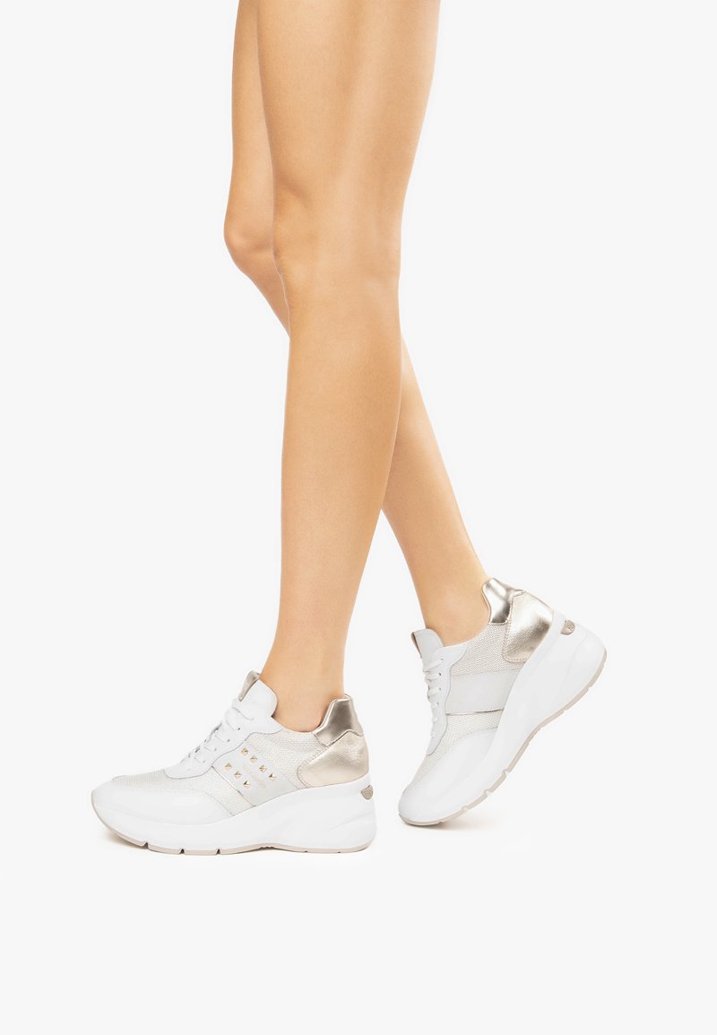 Weiße Sportschuhe mit strukturiertem Mesh und glatten Lederakzenten, ausgestattet mit metallischen Details und einer gepolsterten Sohle für Komfort.