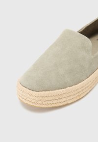 Lys grønn suede slip-on sko med rund tå, med en naturlig taustøvel og en myk tekstur.