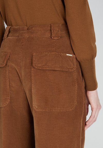 Bruine corduroybroek met een hoge taille, verticale ribbelstructuur en twee achterzakken met subtiele hardwaredetails.