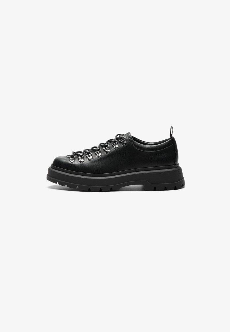 Mustad mustekas nahksneaker, millel on robustne disain, metalldetailidega silmadega, lame paelad ja paks, tekstureeritud kummitald.