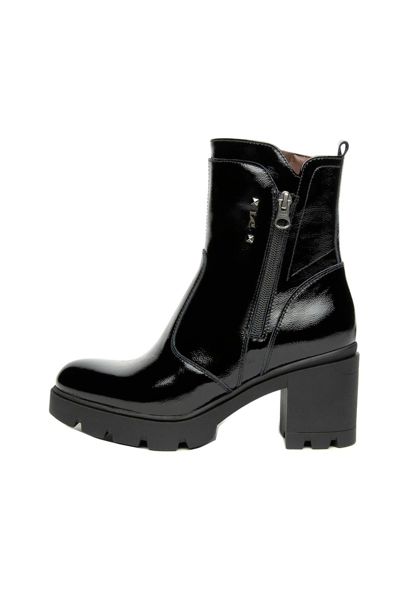Botte de cheville en cuir verni noir avec un talon épais, fermeture à glissière sur le côté et accent clouté à l'avant. Semelle robuste avec des rainures pour l'adhérence.