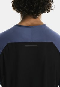 Sinine ja must sportlik särk, tekstuuriga kangast, ümmarguse kaelusega ning peegeldava aktsendiga seljal.