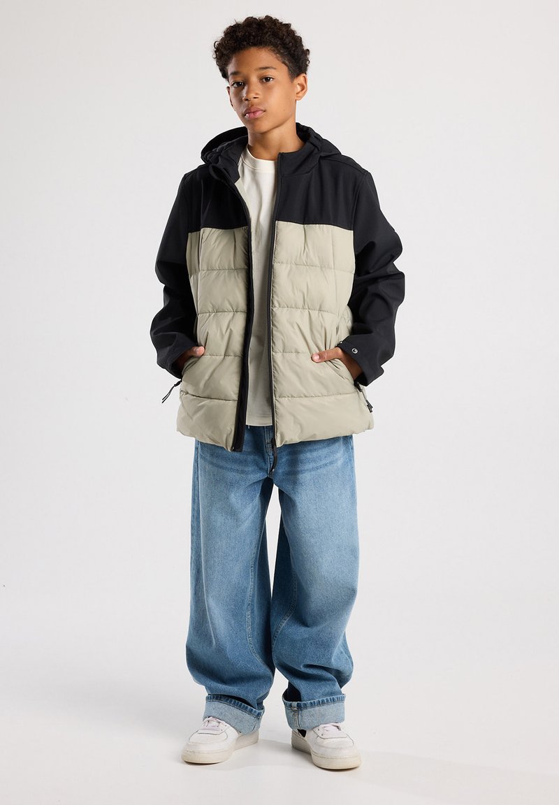 Padded jacket with a black upper and light grey lower portion, featuring a hood, zip closure, and two side pockets. Worn with loose blue jeans.