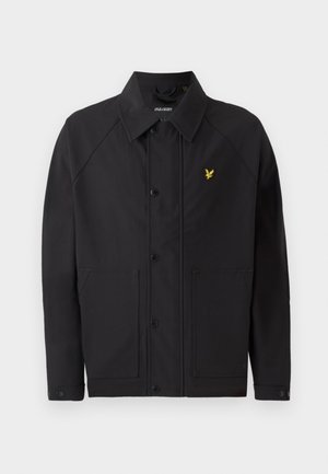 Veste noire avec un col structuré, deux poches avant et un petit logo d'aigle jaune. Fabriquée en tissu lisse et léger.
