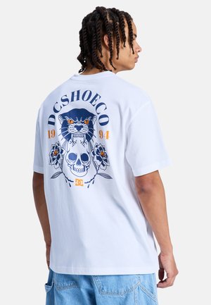 Witte katoenen t-shirt met een grafische print van een schedel, bloemen en een panter in blauw en oranje op de achterkant. Losse pasvorm met korte mouwen.