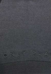 Tamno sivi rebrasti materijal s utisnutim logotipom "ONLY PLAY" na dnu. Tekstura izgleda glatko s blagim sjajem.