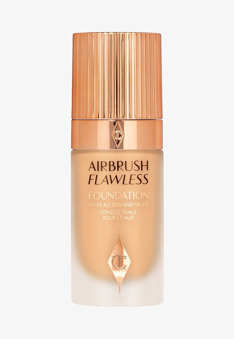 Airbrush Flawless Foundation in einer Glasflasche mit einer verjüngten, gerillten goldenen Kappe; verfügt über gedruckten Text und ein Markenlogo auf der Vorderseite.