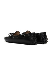 Mocasines de cuero negro con superficie texturizada, detalles de cordones y suelas de caucho con tachuelas. Presentan ojales metálicos para los cordones.