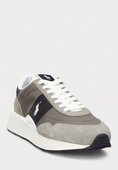 Ανδρικά αθλητικά παπούτσια που διαθέτουν συνδυασμό γκρίζου σουέντ και υφάσματος, λευκές κορδόνες και μια μαύρη πάνελ με λογότυπο στο πλάι και υφή στη σόλα.