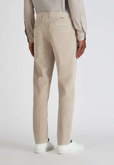 Beige corduroy broek met een rechte pasvorm, voorzien van twee achterzakken en een subtiele textuur. Draagt met witte casual sneakers.