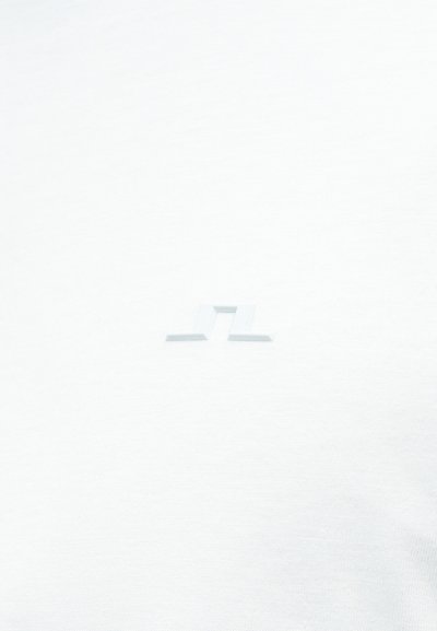 Tissu blanc avec un petit logo géométrique abstrait en relief, centré dans le cadre.