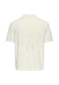 Polo blanc cassé à manches courtes avec un motif texturé en rayons de soleil centré dans le dos.