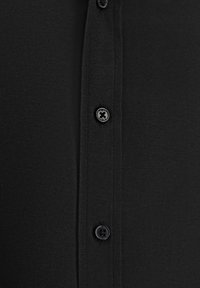 Zwarte overhemd met een gestructureerde stof. Voorzien van een knoopsluiting met zwarte knopen en een kraag, met een eenvoudig, klassiek ontwerp.