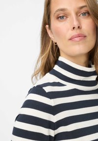 Gestreepte coltrui in marineblauw en wit. Gemaakt van gebreide stof, met een aansluitend ontwerp en een hoge kraag.