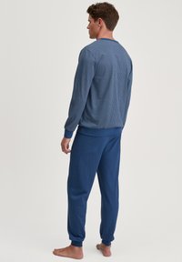 Blauw pyjama set met een getextureerde pullover top met een geometrisch patroon en bijpassende gladde broek; zachte stof, elastische manchetten bij de enkels.