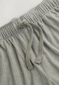 Grau gemusterter Stoff mit einem Fischgrätenmuster und einer strukturierten Oberfläche. Ein elastischer Bund mit einem geknoteten Kordelzug zur Anpassung.