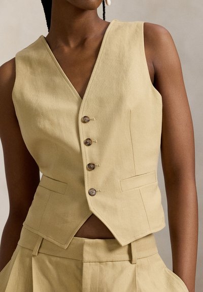 Φωτεινό κίτρινο λινό γιλέκο με V-λαιμόκοψη, πέντε ξύλινα κουμπιά και δύο τσέπες. Διαθέτει αιχμηρό τελείωμα και δομημένη γραμμή.