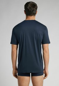 Tmavě modré tričko s krátkým rukávem, hladkým povrchem, kulatým výstřihem a volným střihem, zobrazené ze zadní strany.
