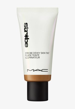 Tube van MAC Strobe Dewy Skin Tint; wit met een bronzen basis, heeft een zwarte dop en vetgedrukte zwarte tekst aan de voorkant. Zachte textuur.