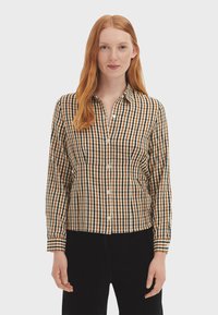 Button-up shirt with a brown and beige plaid pattern, long sleeves, and a collar. Made of lightweight cotton fabric.