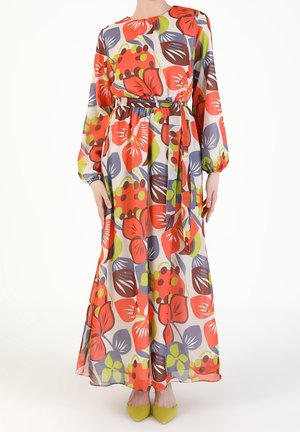 Langärmliges Kleid mit Gürtel und auffälligem Blumenmuster in Rot, Braun, Grün und Lila, kombiniert mit gelben Schuhen mit spitzer Spitze.