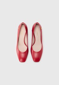 Piros bőr lapos cipők sima textúrával, négyzet alakú orrész dizájnnal és finom arany logó díszítéssel. Belső rész világos bézs színű.