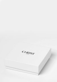 Vit rektangulär låda med lock, med märket "CHRIST" och "sedan 1863" tryckt i svart text på framsidan. Slät textur.