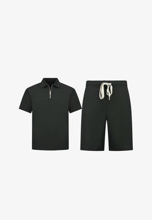 Zwart poloshirt met korte mouwen en een rits aan de voorkant en zwarte elastische taille shorts met wit trekkoord.