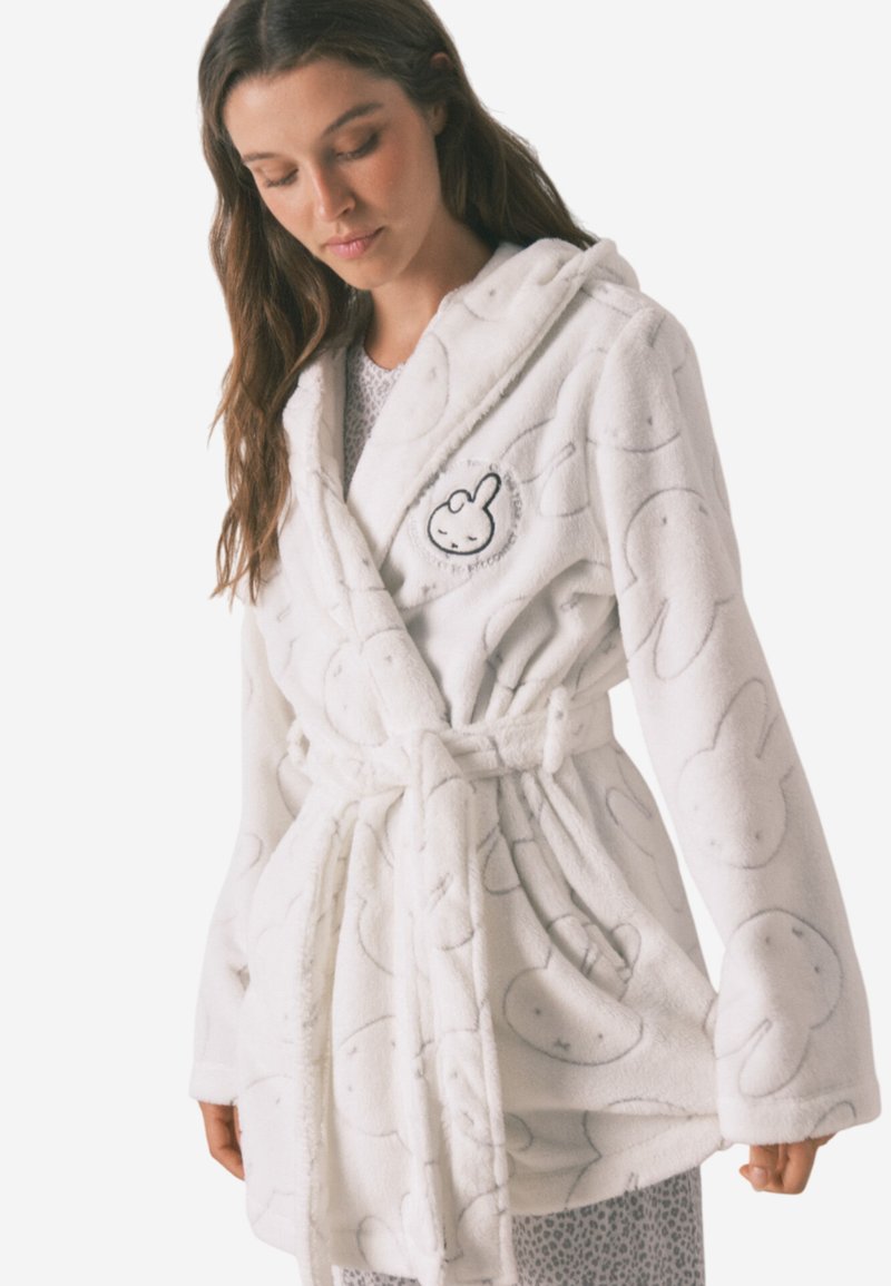 Hvid fleece badekåbe med kaninmønster, hætte, frontlommer og bælte. Blød tekstur og broderet kanindetalje på brystet.
