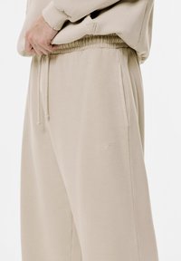 Beige Sweatpants aus weichem Stoff. Verfügt über einen elastischen Bund, eine Kordel und eine dezente Logo-Stickerei am Oberschenkel.