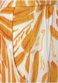 Tissu à motifs floraux avec des feuilles orange vif et jaunes sur un fond blanc ; texturé avec de fines rayures verticales et des plis.