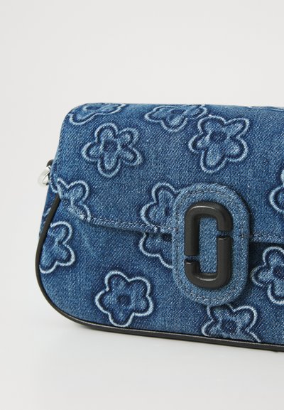 Jeans torba s cvjetnim vezom, tamnoplave boje, pravokutnog oblika, s magnetskim zatvaranjem i crnim logotipom sprijeda.