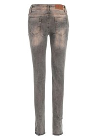 Vervaagde grijze denim jeans met een slim fit, rafelige zoom en twee achterzakken. Heeft een bruine leren patch op de tailleband.