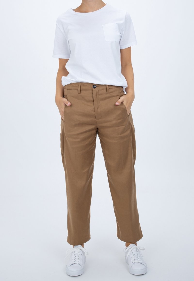 White short-sleeve t-shirt with a chest pocket, paired with brown wide-leg trousers and white sneakers, featuring a smooth fabric texture.