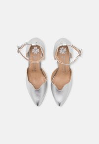 Paire de ballerines argentées métalliques à bout pointu avec brides à la cheville sur fond blanc, taille 37 indiquée à l'intérieur des chaussures.