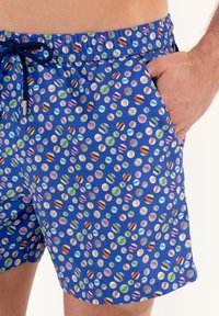 Shorts de bain bleus avec un motif marbré multicolore, dotés d'une taille élastique et de poches latérales, fabriqués en tissu léger.