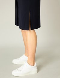 Marineblaues Midikleid mit Seitenschlitzen, kombiniert mit weißen Plateau-Sneakern. Weicher, geschmeidiger Stoff, lockere Passform und dezente Nähte.