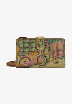 Multikleurige portemonnee met een illustratie van een roze fiets, bloemaccenten, een baksteengevelontwerp en een bruine strap. Textuur oppervlakte met ritssluiting.