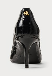 Μαύρο παπούτσι με γυαλιστερό δέρμα, ψηλοτάκουνο, με υφή κροκοδείλου, διακοσμημένο με το χρυσό λογότυπο "RL" στο πίσω μέρος και μυτερή μύτη.