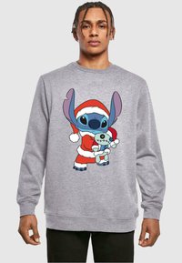 Felpa grigia con un personaggio dei cartoni animati in un costume da Babbo Natale rosso, che tiene un giocattolo azzurro. Tessuto morbido con polsini e orlo a coste.