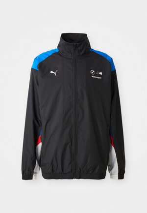 Zwarte jas met blauwe, rode en witte accenten. Voorzien van ritssluiting, hoge kraag, elastische manchetten en logo's op de voorkant. Lichtgewicht materiaal.