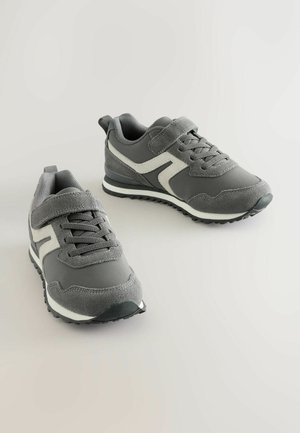 Grå sportssko med en kombination af tekstureret stof og glat ruskind, med hvide accenter, snørebånd og en velcrolukning.