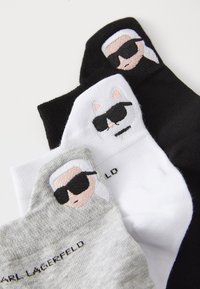 Three pairs of socks: one black with a character, one white with a cat design, and one gray featuring a character, all with embroidered details.