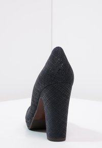 Zapato de tacón alto azul oscuro con una superficie texturizada y con patrón, punta redondeada y tacón grueso. Confeccionado en materiales sintéticos.