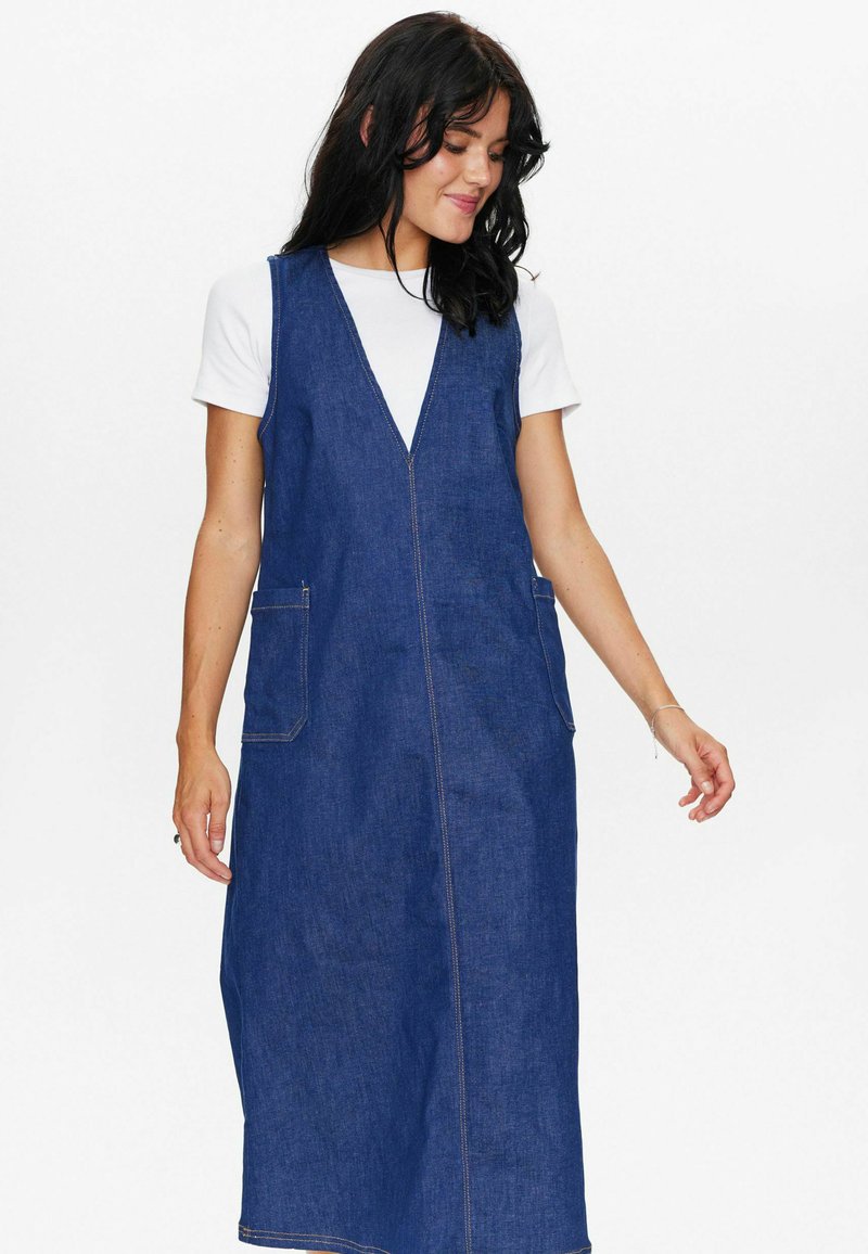 Denim overall obleka, v nakitu v obliki črke V, brez rokavov, z dvema stranskima žepoma, temno modre barve, vidni šivi, raven silhueta.