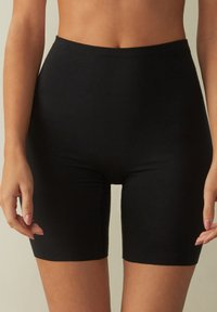 Schwarze Stretch-Shorts mit hoher Taille, aus einem glatten Material gefertigt, mit einem taillierten Schnitt, der bis zur Mitte des Oberschenkels reicht.