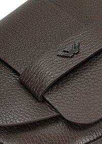 Borsa in pelle marrone con texture, caratterizzata da una chiusura a pattina e un piccolo logo in metallo nero sul davanti. Superficie liscia e resistente.