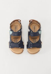 Navy blue leather sandals with adjustable straps, tan footbed, white and light blue accents, and rubber soles. Brand label visible inside.