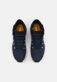 Zapatos de senderismo en color navy con parte superior de malla, acentos negros, ojales plateados y cordones texturizados; plantilla naranja con la marca Timberland.